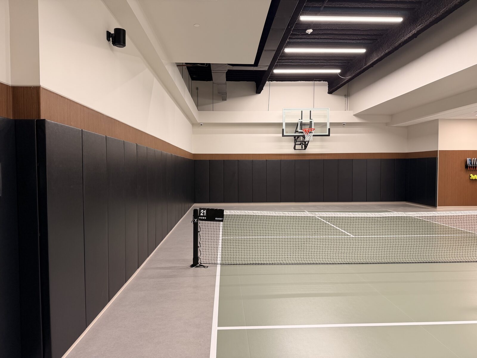 Draper wall pads protecting the perimeter of an indoor sport court with basketball hoop